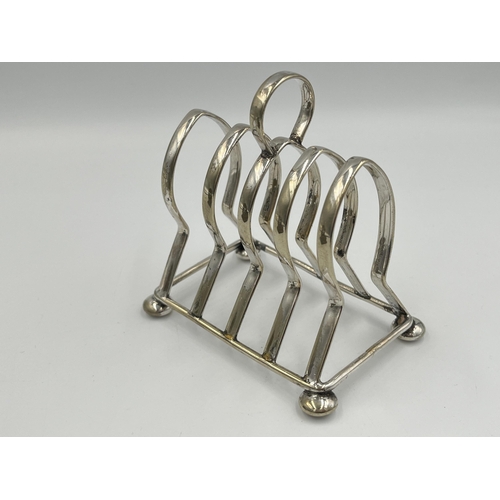 2114 - Two items, one Art Nouveau brass lidded stamp holder and one silver plated four slice toast rack