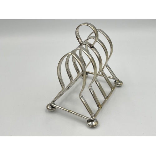 2114 - Two items, one Art Nouveau brass lidded stamp holder and one silver plated four slice toast rack