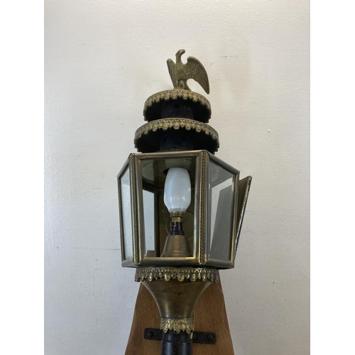 463 - A late 19th/early 20th century brass and black metal carriage lamp with eagle design top and later a... 