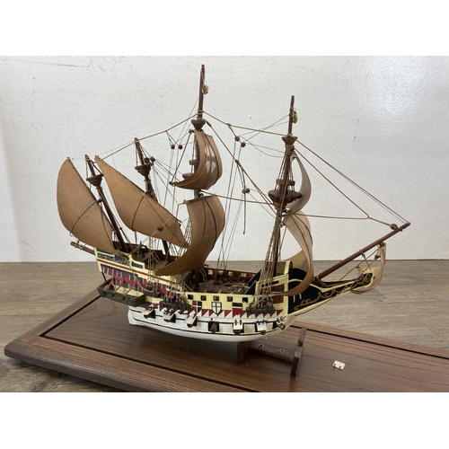 525 - A hand painted wooden model ship with glass case and oak plinth - approx. 35cm high x 20cm wide x 58... 