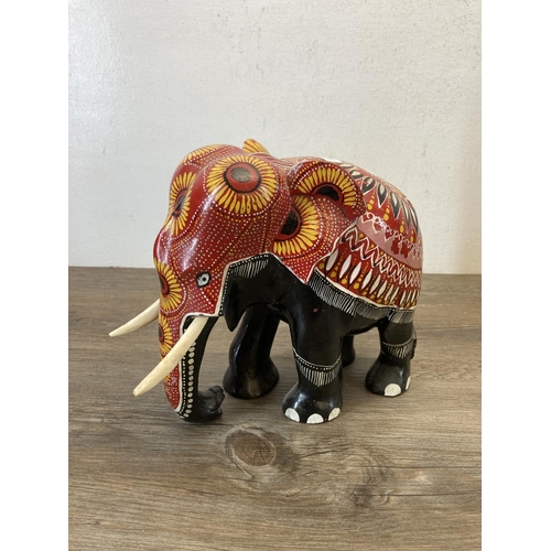 556 - Two hand painted and carved wooden elephant figurines - largest approx. 33cm high