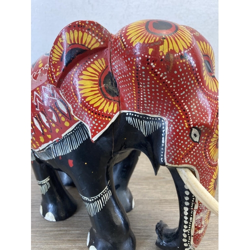 556 - Two hand painted and carved wooden elephant figurines - largest approx. 33cm high