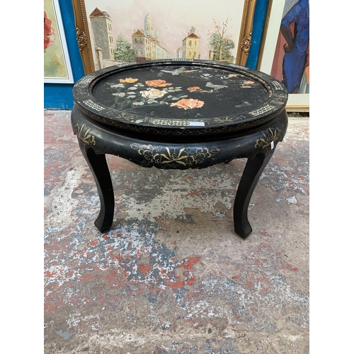 79 - An Oriental black lacquered and mother of pearl inlaid circular coffee table with bird and foliate r... 