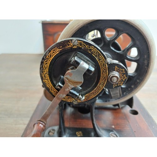 858 - A cased late 19th century Bradbury & Company Limited hand-crank fiddle-base sewing machine with inst... 