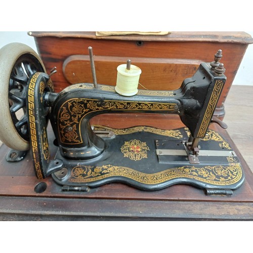 858 - A cased late 19th century Bradbury & Company Limited hand-crank fiddle-base sewing machine with inst... 