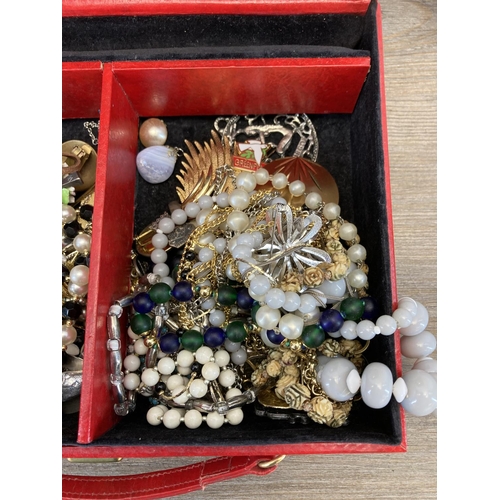 513 - A red faux leather jewellery box containing a collection of assorted costume jewellery to include 19... 