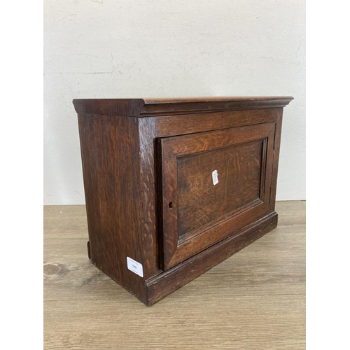 579 - An early 20th century oak single door cabinet - approx. 30cm high x 39.5cm wide x 20cm deep