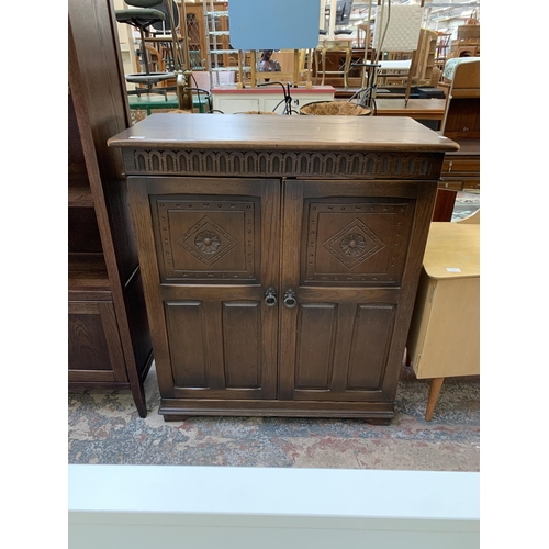 106 - A carved oak two door TV cabinet - approx. 105cm high x 90cm wide x 46cm deep