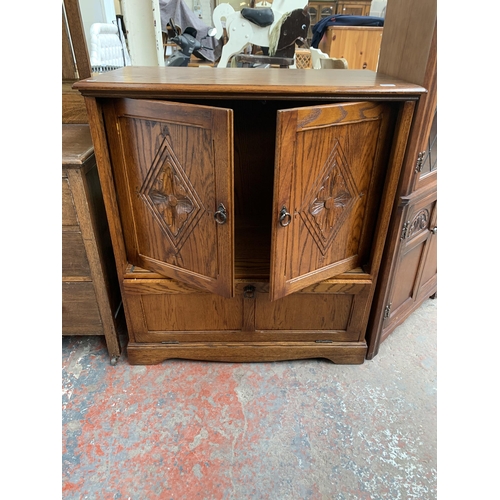 177 - A carved oak TV cabinet - approx. 104cm high x 94cm wide x 53cm deep