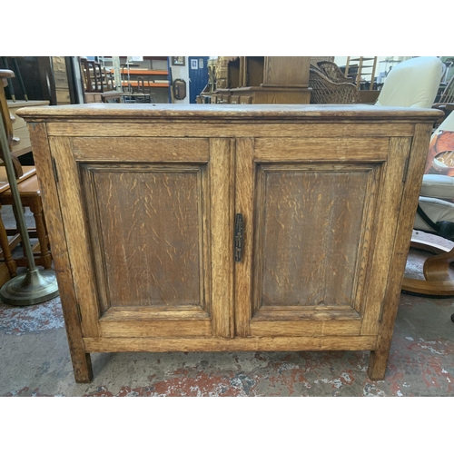 227 - A 1930s oak two door cabinet - approx. 77cm high x 93cm wide x 45cm deep