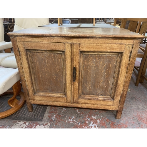 227 - A 1930s oak two door cabinet - approx. 77cm high x 93cm wide x 45cm deep