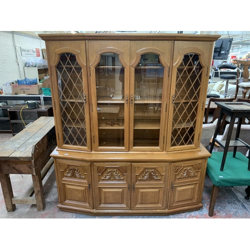 244 - A large 20th century teak display cabinet with carved floral motives - approx. 200cm high x 180cm wi... 