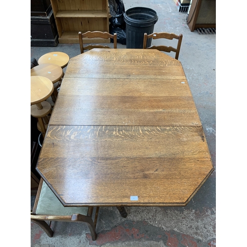 260 - An early 20th century oak drop leaf gate leg dining table on barley twist supports and four oak ladd... 