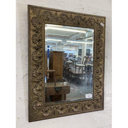 662 - An early/mid 20th century embossed brass framed bevelled edge wall  mirror - approx. 56cm high x 43c... 