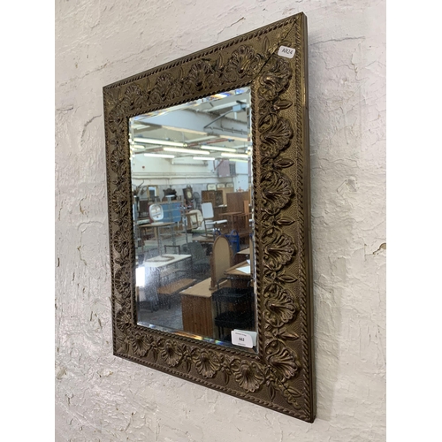 662 - An early/mid 20th century embossed brass framed bevelled edge wall  mirror - approx. 56cm high x 43c... 