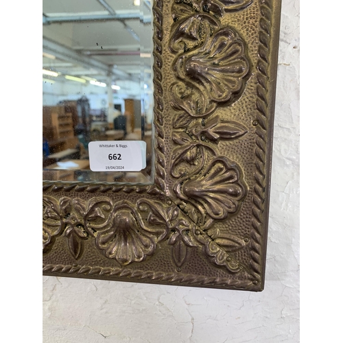 662 - An early/mid 20th century embossed brass framed bevelled edge wall  mirror - approx. 56cm high x 43c... 