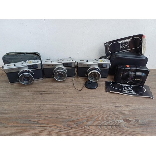 690 - Four Olympus compact 35mm cameras, three Trip 35 and one XA with instruction manual