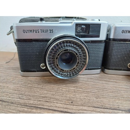 690 - Four Olympus compact 35mm cameras, three Trip 35 and one XA with instruction manual