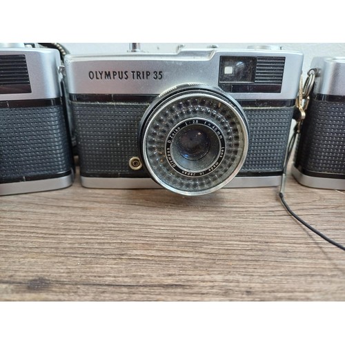 690 - Four Olympus compact 35mm cameras, three Trip 35 and one XA with instruction manual