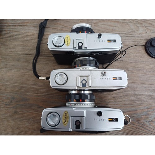 690 - Four Olympus compact 35mm cameras, three Trip 35 and one XA with instruction manual