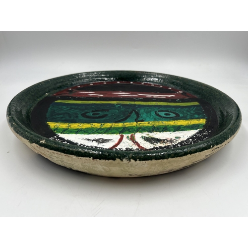 384 - A John Piper studio pottery charger with outré face decoration - approx. 29cm diameter