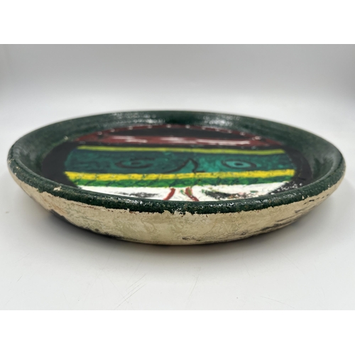 384 - A John Piper studio pottery charger with outré face decoration - approx. 29cm diameter