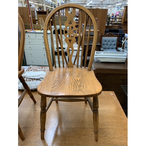 78 - A mid 20th century oak rectangular trestle dining table and four wheel back chairs - table approx. 7... 