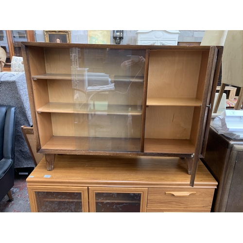 97 - A mid 20th century oak veneer bookcase with two glass sliding doors - approx. 79cm high x 107cm wide... 