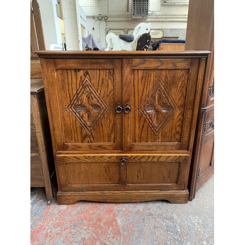 144 - A carved oak TV cabinet - approx. 104cm high x 94cm wide x 53cm deep