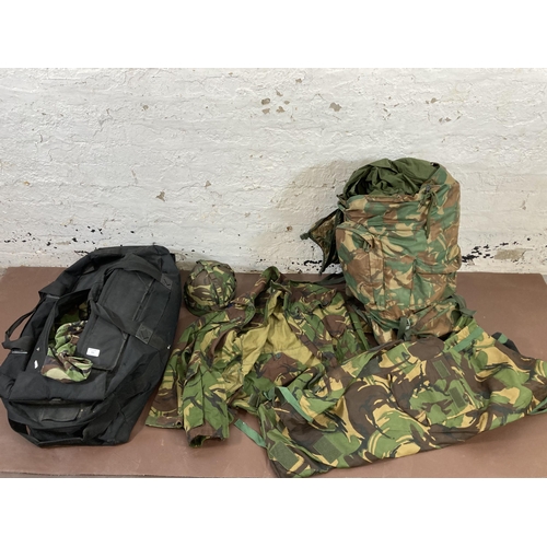 430 - A large quantity of camouflage military uniform and accessories to include Wynnster rucksack, helmet... 