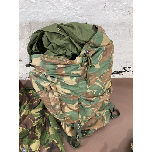 430 - A large quantity of camouflage military uniform and accessories to include Wynnster rucksack, helmet... 