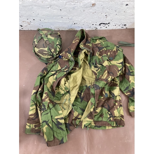 430 - A large quantity of camouflage military uniform and accessories to include Wynnster rucksack, helmet... 