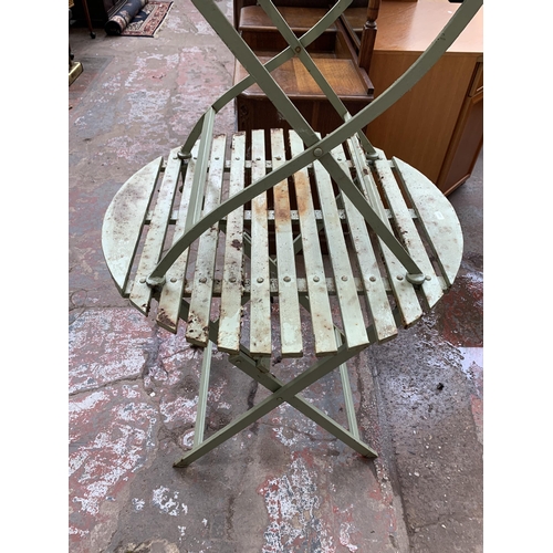 134 - A green painted metal folding two piece bistro set comprising circular table and chair