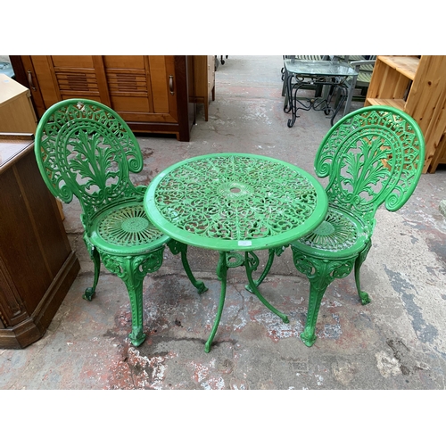 136 - A Victorian style green painted cast metal three piece patio set - table approx. 62cm high x 66cm di... 