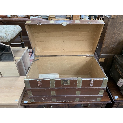 157 - An early 20th century brown painted fibreboard dome top travel trunk with wooden and brass banding -... 