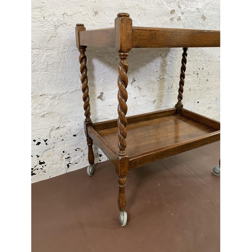 169 - A mid 20th century oak barley twist two tier tea trolley - approx. 70cm high x 38cm wide x 61cm long