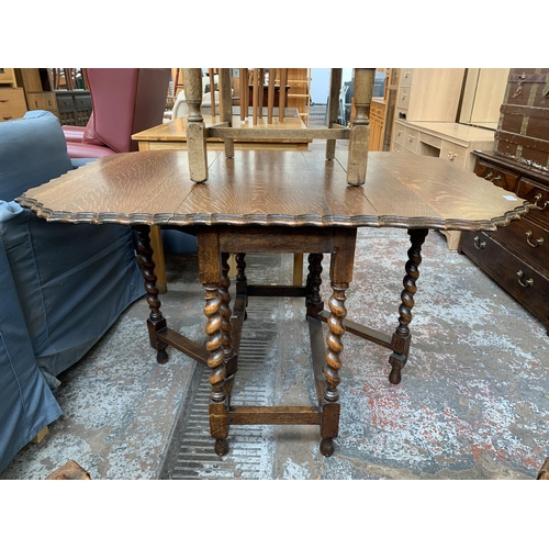 180 - An early 20th century oak pie crust edge drop leaf gate leg dining table on barley twist supports an... 