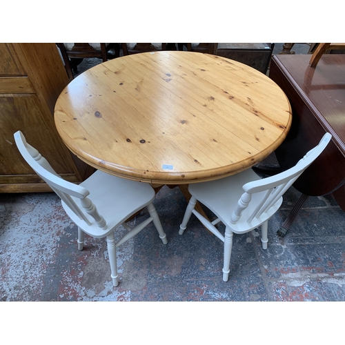 209 - A modern pine circular extending dining table and two white painted spindle back chairs - table appr... 