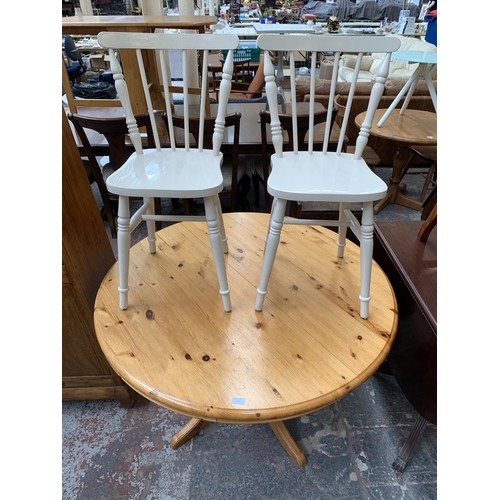 209 - A modern pine circular extending dining table and two white painted spindle back chairs - table appr... 