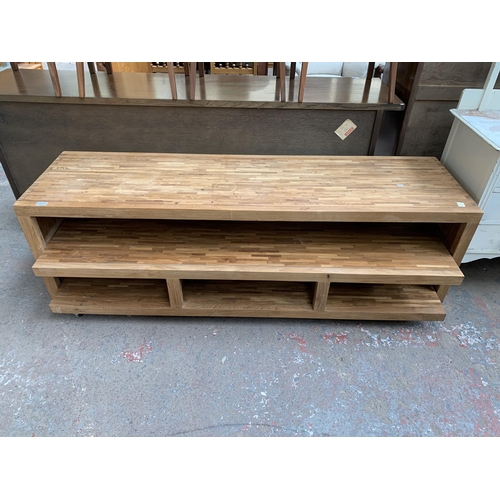 225 - A modern solid oak TV stand with removable storage compartment on castors - approx. 54cm high x 180c... 