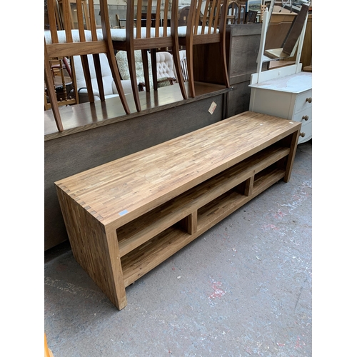 225 - A modern solid oak TV stand with removable storage compartment on castors - approx. 54cm high x 180c... 