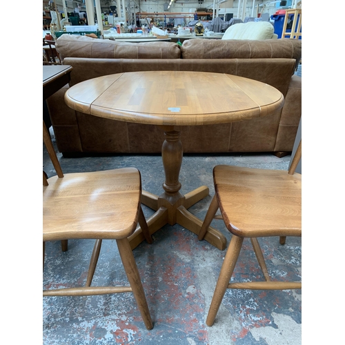 239 - A modern beech circular drop leaf dining table and two chairs - approx. 75cm high x 91cm diameter