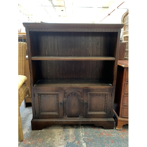 30 - A carved oak two tier bookcase - approx. 102cm high x 84cm wide x 25cm deep