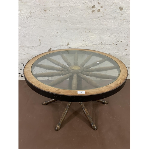 42 - A mid 20th century oak and glass top revolving ships wheel coffee table - approx. 42cm high x 74cm w... 