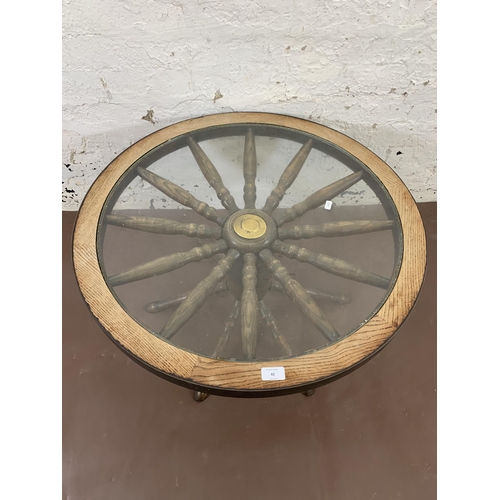 42 - A mid 20th century oak and glass top revolving ships wheel coffee table - approx. 42cm high x 74cm w... 