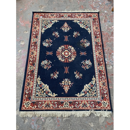 83 - A mid/late 20th century red and blue machine woven rug - approx. 165cm x 119cm