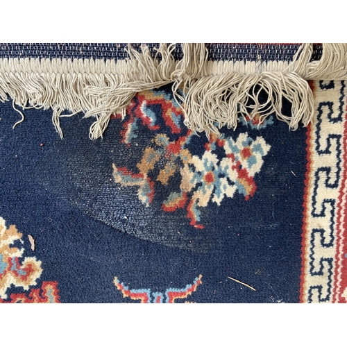 83 - A mid/late 20th century red and blue machine woven rug - approx. 165cm x 119cm