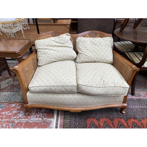 99 - A carved beech and rattan two seater bergere sofa - approx. 77cm high x 121cm wide x 74cm deep