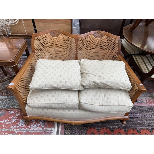 99 - A carved beech and rattan two seater bergere sofa - approx. 77cm high x 121cm wide x 74cm deep