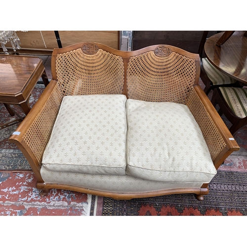 99 - A carved beech and rattan two seater bergere sofa - approx. 77cm high x 121cm wide x 74cm deep